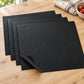 Four black Grill&Chill BBQ mats fanned out on an oak table