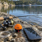 SonarKule on a wet rock next to a phone and fishing reel – the size of a tennis ball